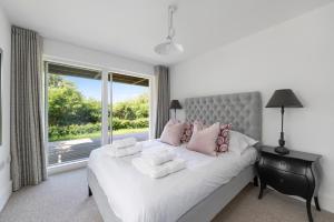 une chambre avec un grand lit blanc avec une fenêtre dans l'établissement NEW Bauhinia House Spa Access and Lakeside Home, à Somerford Keynes 73 autres photos