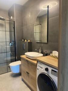 a bathroom with a sink and a washing machine at P R A T U M Plus in Mikołajki +43 photos