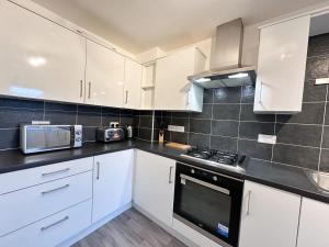 Una cocina con gabinetes blancos y un horno de estufa. en Densham House by Blue Skies Stays, en Stockton-on-Tees 15 fotos más