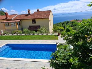 a swimming pool in front of a house at Casa Andrea in Mošćenička Draga
