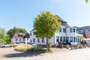 a tree in front of a white building at Hotel Villa Sonneck-Adults Only in Sankt Peter-Ording