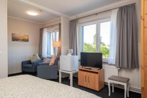a hotel room with a bed and a tv and a chair at Hotel Villa Sonneck-Adults Only in Böhl