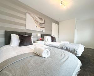 two beds in a large room with white and gray at Turton House by Blue Skies Stays in Stockton-on-Tees
