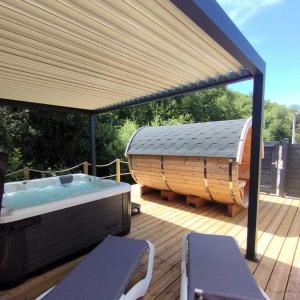 a hot tub sitting on a deck with a roof at ZEcamping 3 étoiles animaux acceptés piscine chauffée restaurant et soirées in Huelgoat +41 photos
