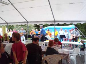 un groupe de personnes assises à des tables sous une tente dans l'établissement Camping 3 étoiles - Piscine - ccafbbc, à Huelgoat 127 autres photos