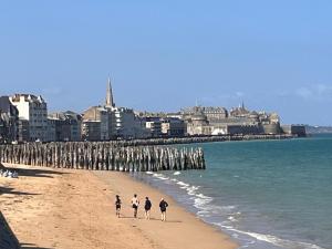 three people walking on the beach near the ocean at Le Cézembre, au pied de la plage in Saint Malo