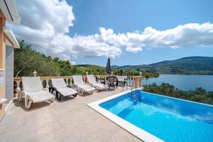 a patio with a pool and chairs and a view of a lake at Holiday Home Nina Plitvine in Vela Luka