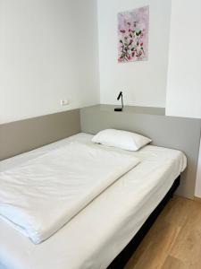 ein Bett mit weißen Laken und einer Lampe darauf in der Unterkunft Hotel Wasserpalast - breakfast for free!!! in Graz