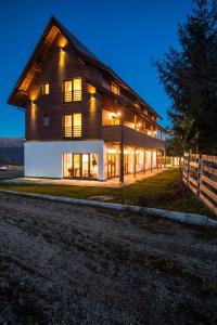 a large wooden house with lights on at Soare-n Maramureș in Budeşti