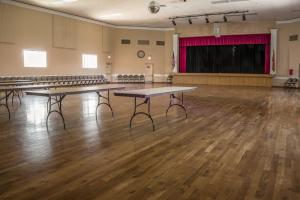 une grande salle avec des tables et une scène avec des chaises dans l'établissement Sunland Village, à Mesa