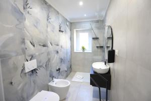 a bathroom with a white toilet and a sink at Don Peppe Rooms With Beach Service Included in Tropea