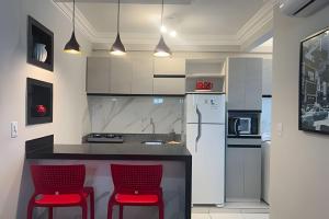 une cuisine avec deux chaises rouges à un comptoir dans l'établissement 403 Apto Versátil e Aconchegante, à Belém