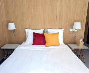 una cama blanca con dos almohadas rojas y amarillas en Hôtel d'Angleterre, en Versalles