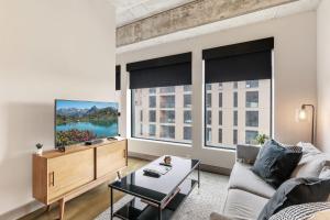 Una sala de estar con un sofá y un televisor y dos ventanas grandes. en Sable 403 - Alcove, en Minneapolis