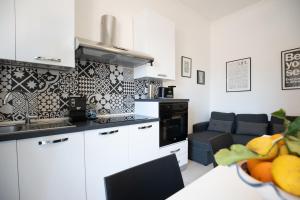 a kitchen with white cabinets and a living room at Catania Over Time - Tourist Rooms in Catania