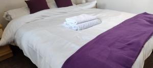 a white bed with two towels sitting on it at Entire 2 bedroom home with parking in Coventry, UK in Coventry