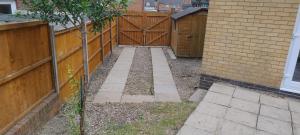 a backyard with a fence and a wooden gate at Entire 2 bedroom home with parking in Coventry, UK in Coventry