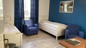 a room with two beds and two blue chairs at Hostel Apartment in Castrop-Rauxel