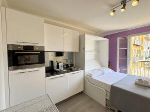 a small kitchen with white cabinets and a bed at ApartHotel Riviera Nice Côte d'Azur - Old Town - Studio AC - Sea View - 50m Promenade des Anglais- LA MAISON LINDA in Nice