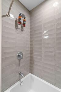 a bathroom with a tub and a shower with two bottles at Sable 604 - One Bedroom in Minneapolis +35 photos