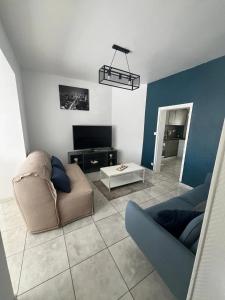 a living room with a couch and a tv at Charmante maison à Lagord avec jardin privatif in Lagord