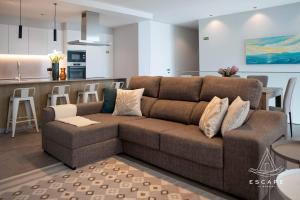 a living room with a brown couch and a kitchen at Villa Nicuma by ESCAPE to Madeira in Calheta