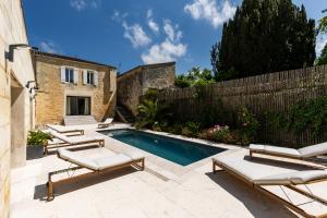 Una piscina con tumbonas al lado de una casa. en La Girondine - Piscine, billard, vigne et estuaire, en Gauriac