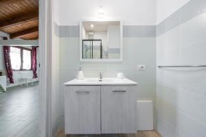 a white bathroom with a sink and a mirror at Confortevole Loft Sud Sardegna in San Giovanni Suèrgiu +15 photos