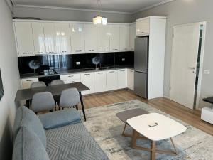 a kitchen with white cabinets and a table and a couch at Liqeni New Apartament in Tirana