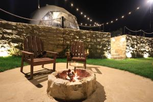 two chairs sitting next to a fire pit at night at Nomaddome Glamping Hotel in Mishmish