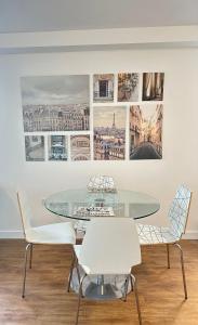a glass table and chairs in front of a wall with pictures at Amazing 2 Bed Flat With City Views in Barking