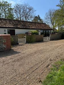 a house with a fence and a gravel driveway at Elm Barn in Diss