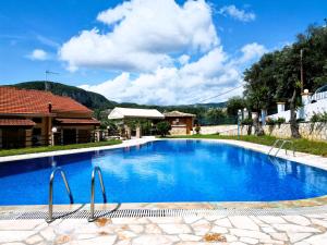 a large blue swimming pool with a house in the background at Villa Michalis Goulis in Liapades