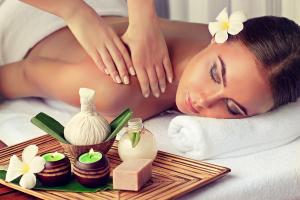 a woman laying on a bed with a tray of spa products at Le pigeonnier in Le Verdier