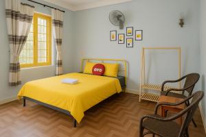 a bedroom with a yellow bed with a red pillow on it at Happy House Homestay in Hue