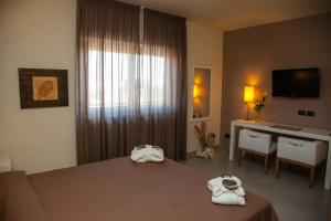 a hotel room with a bed, table and a television at 4 Spa Resort Hotel in Catania