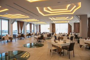 a restaurant with white tables and chairs and windows at 4 Spa Resort Hotel in Catania