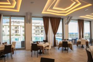 カターニアにある4 スパ リゾート ホテルのテーブルと椅子と大きな窓のあるレストラン