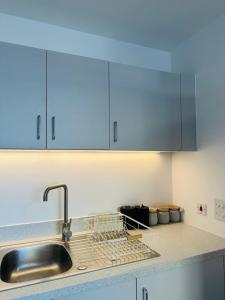 a kitchen with a sink and a dish rack at Amazing 2 Bed Flat With City Views in Barking