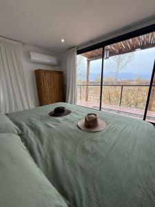 two hats on a bed in a bedroom with a window at La Viñita Wine Lodge in La Consulta
