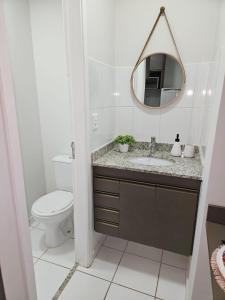 a bathroom with a sink and a toilet and a mirror at 1027 Apartamento Luxuoso! in Ribeirão Preto