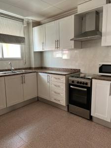 a kitchen with white cabinets and a stove top oven at Apartamento CA VALEN 3 in Peñíscola