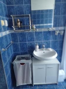 a blue tiled bathroom with a sink and a toilet at Vila 'Anna' in Krapets