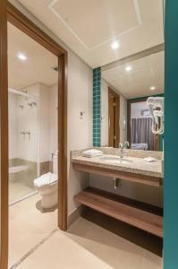 a bathroom with a sink and a toilet and a mirror at Enjoy Olimpia Park Resort in Olímpia
