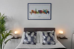 a bedroom with a bed with two lamps and a picture on the wall at City Centre Studio Apartments - Stoop Apartment - Short Stays UK Ltd in Exeter