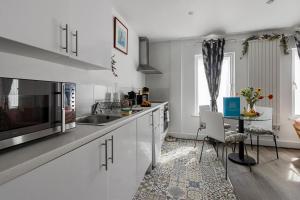 a kitchen with white cabinets and a table at City Centre Studio Apartments - Stoop Apartment - Short Stays UK Ltd in Exeter
