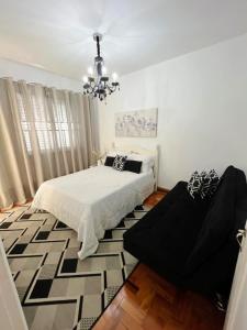 a bedroom with a bed and a chandelier at Aconchegante apt Florença no centro com vaga coberta in Serra Negra