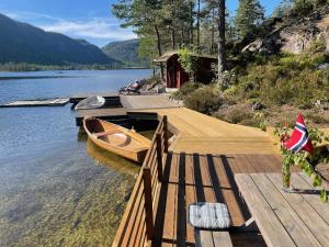 a wooden dock with a boat on the water at Sommeridyll i vannkanten in Bygland