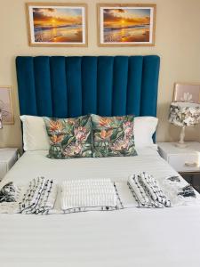 a bed with a blue headboard and pillows on it at PrimVilla Apartment in Gaborone