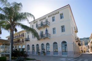 un grand bâtiment blanc avec un palmier en face dans l'établissement Grande Bretagne - Nafplio, à Nauplie